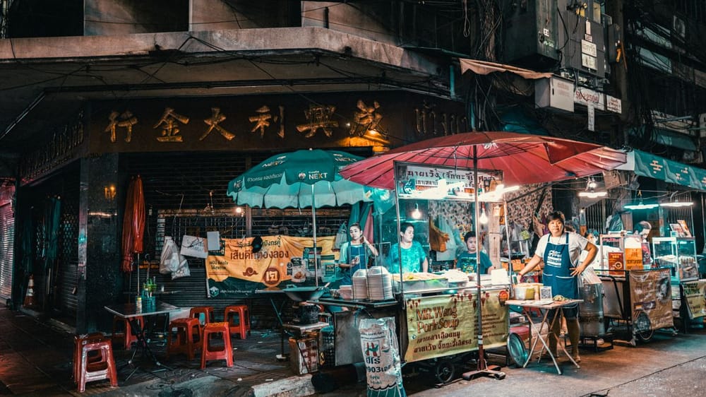 Vibrant night market scene in Bangkok showcasing street food vendors and bustling activity.