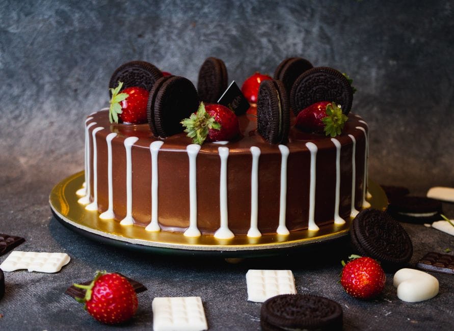 A rich, decadent chocolate cake topped with Oreo cookies and fresh strawberries, perfect for dessert lovers.
