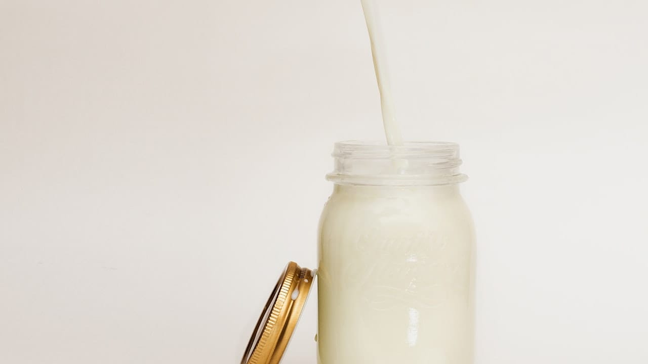 Wooden bowl of oats with milk jug on rustic table. Ideal for health-focused breakfast imagery.