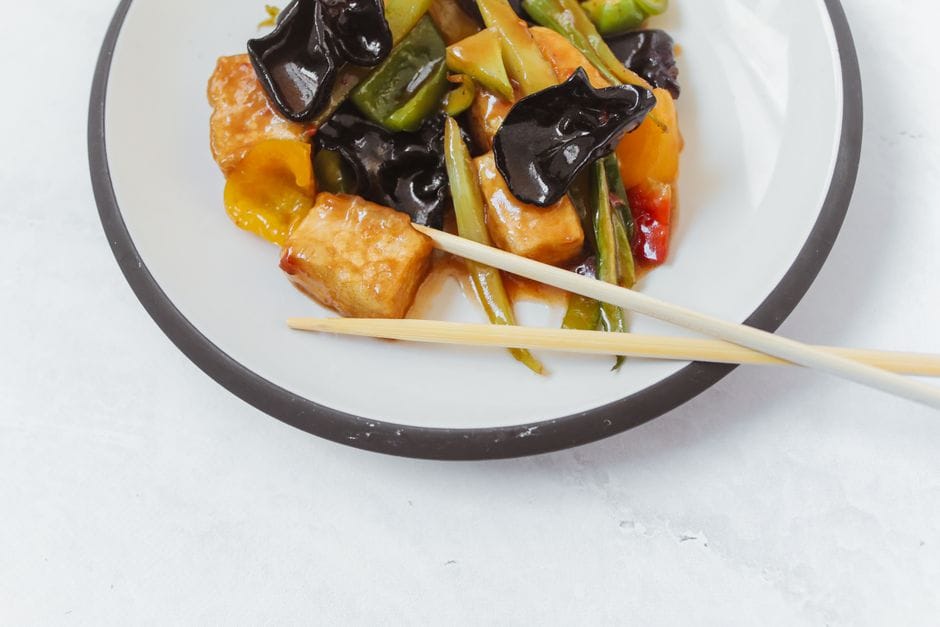 Close-up of a delicious tofu stir fry with vegetables on a white plate, perfect for food photography.
