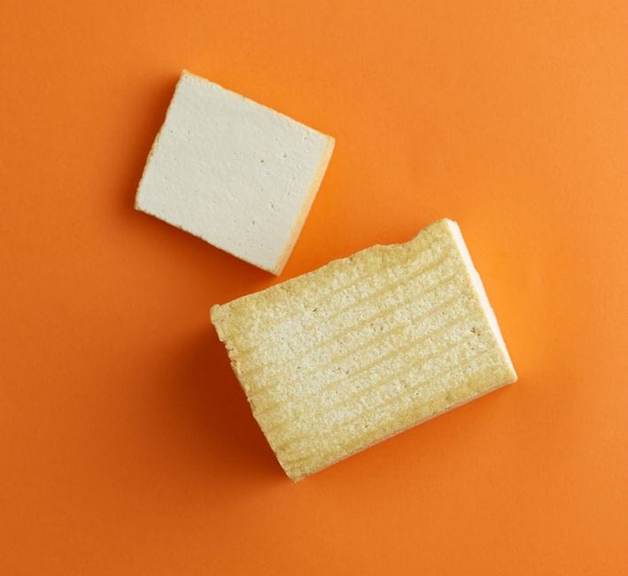 High-quality photo of tofu blocks on an orange backdrop, perfect for food blogs or advertisements.