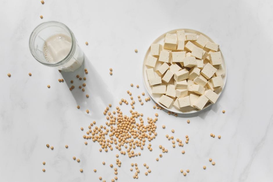 Top view of tofu cubes, soybeans, and soy milk on a white background, perfect for vegan food themes.
