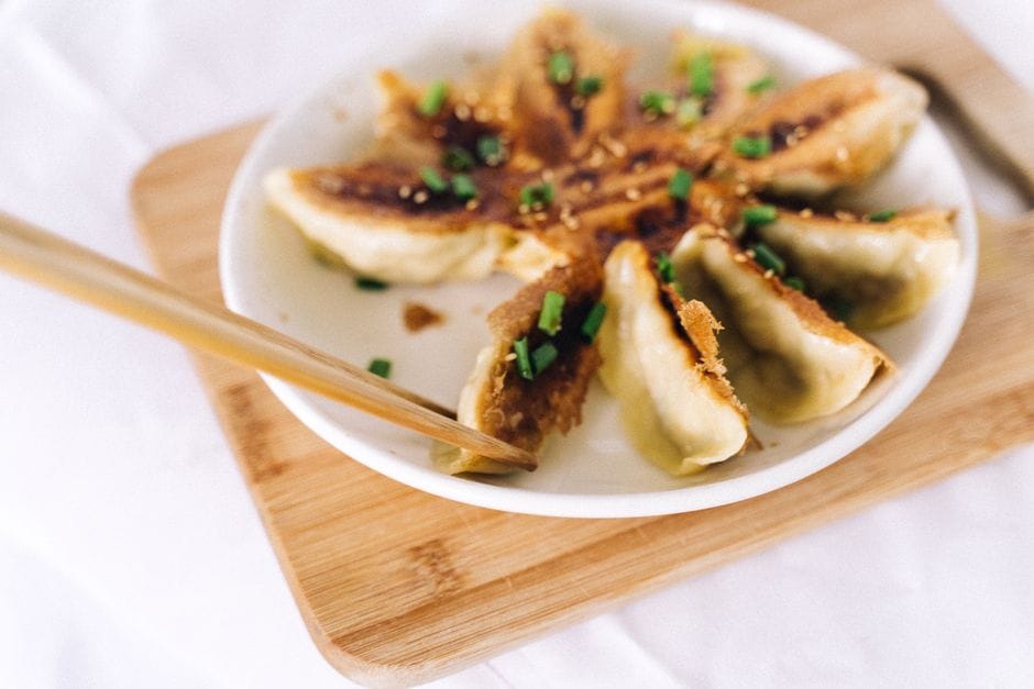 Close-up of crispy gyoza dumplings garnished with scallions and soy sauce.