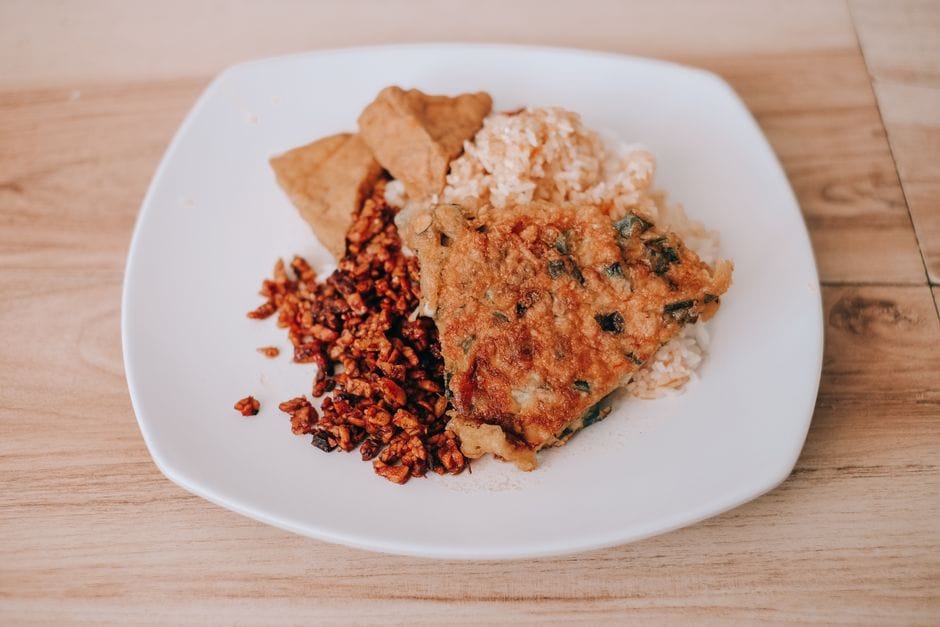 Delicious Indonesian tempeh and rice served on a white plate, showcasing traditional flavors and textures.