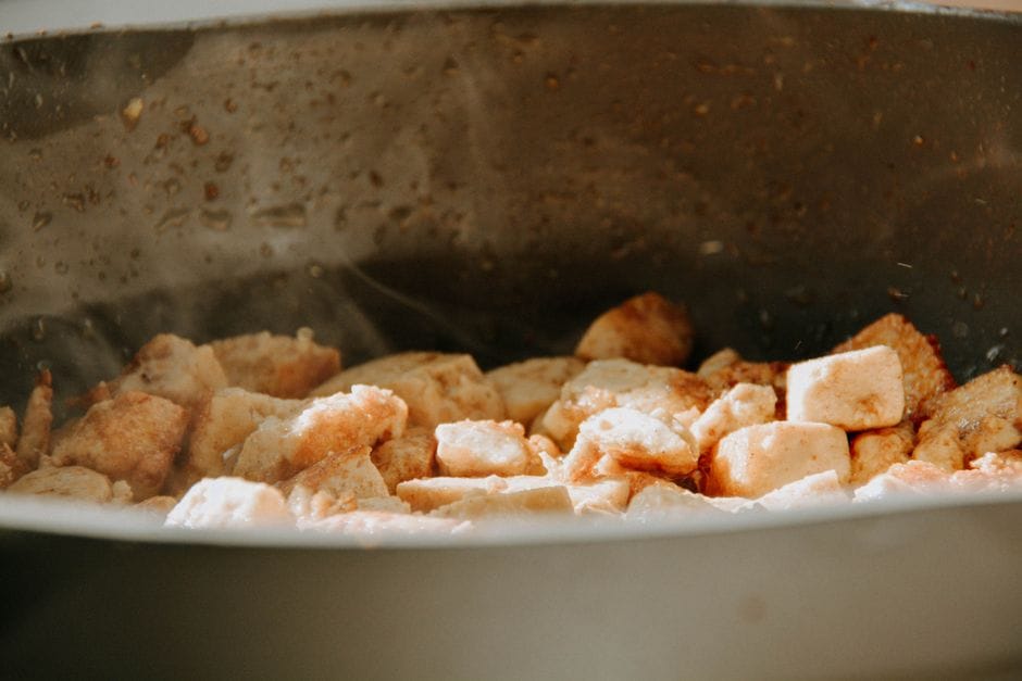 A close-up view of tofu cubes being cooked in a frying pan.