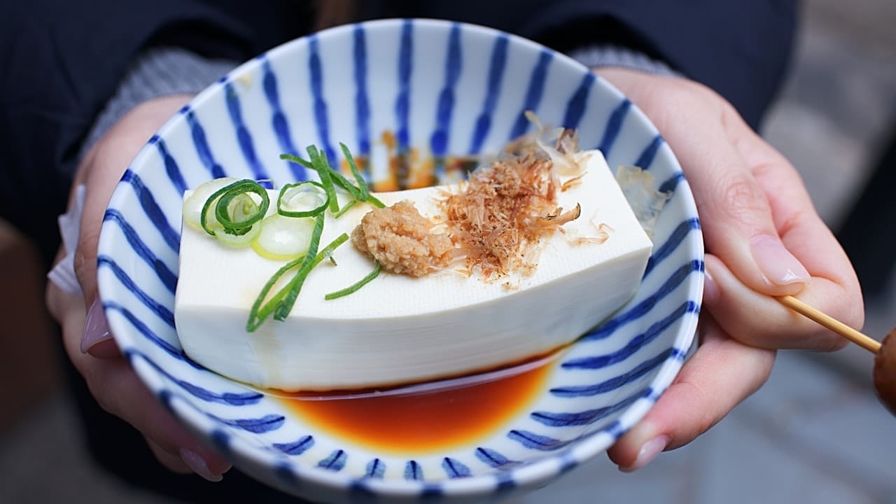 Flat lay of tofu cubes drizzled with soy sauce and sprinkled with sesame seeds.