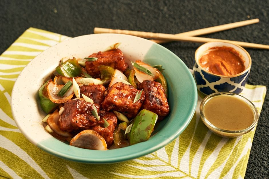 A vibrant bowl of stir-fried tofu with vegetables, garnished with green onions. Perfect for an appetizing meal.