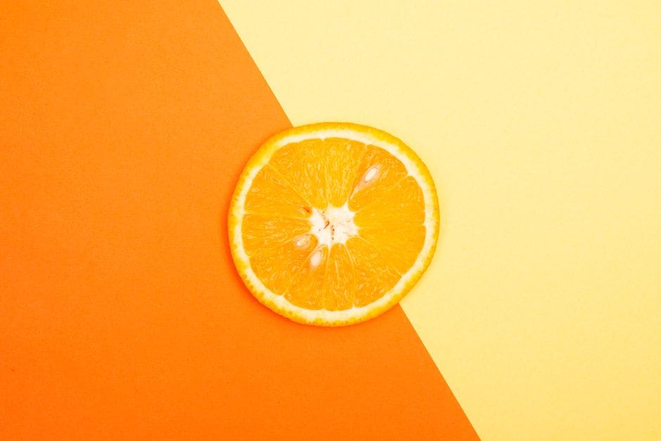 Bright and juicy orange slice set against a vibrant yellow and orange background, perfect for fresh and healthy themes.