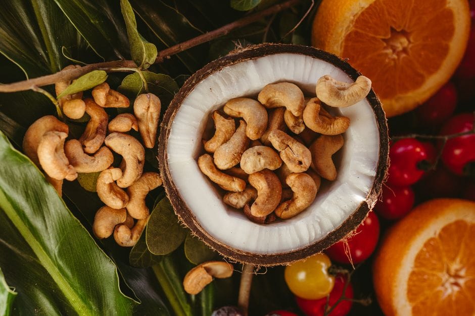 Delicious cashews in a coconut shell with tropical fruits. Perfect healthy snack.