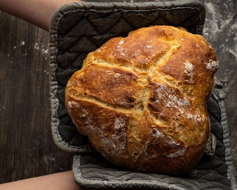 Golden crusted artisan bread resting on a wooden surface, showcasing home-baked perfection.