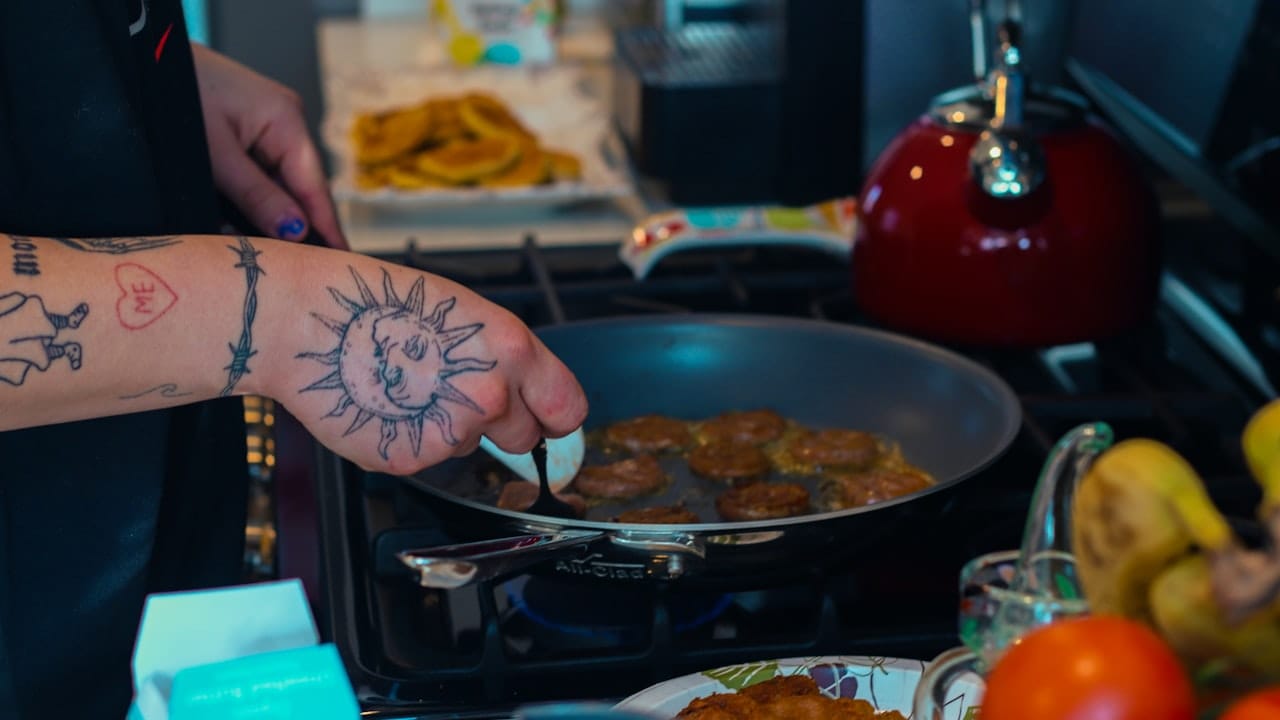 a person with a tattoo on their arm cooking food