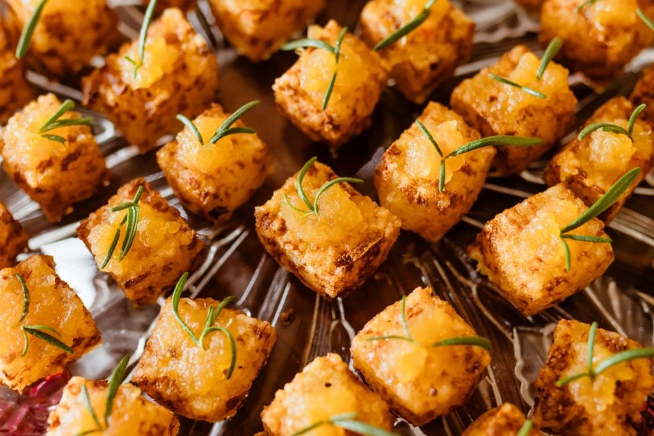 Tasty baked tofu cubes garnished with fresh rosemary, perfect for vegan parties.
