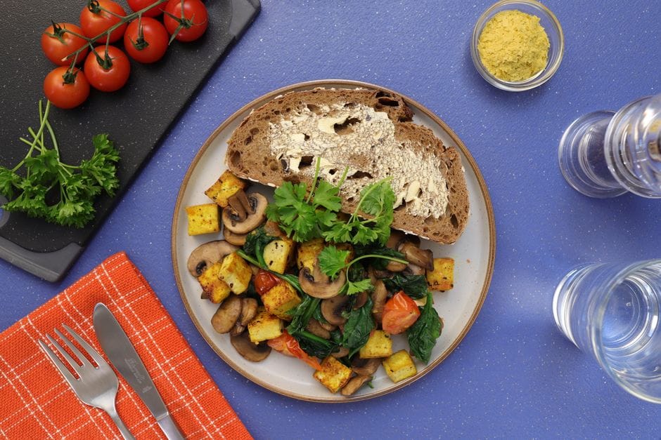Top view of a vegan breakfast with bread, tofu, and veggies on a plate.