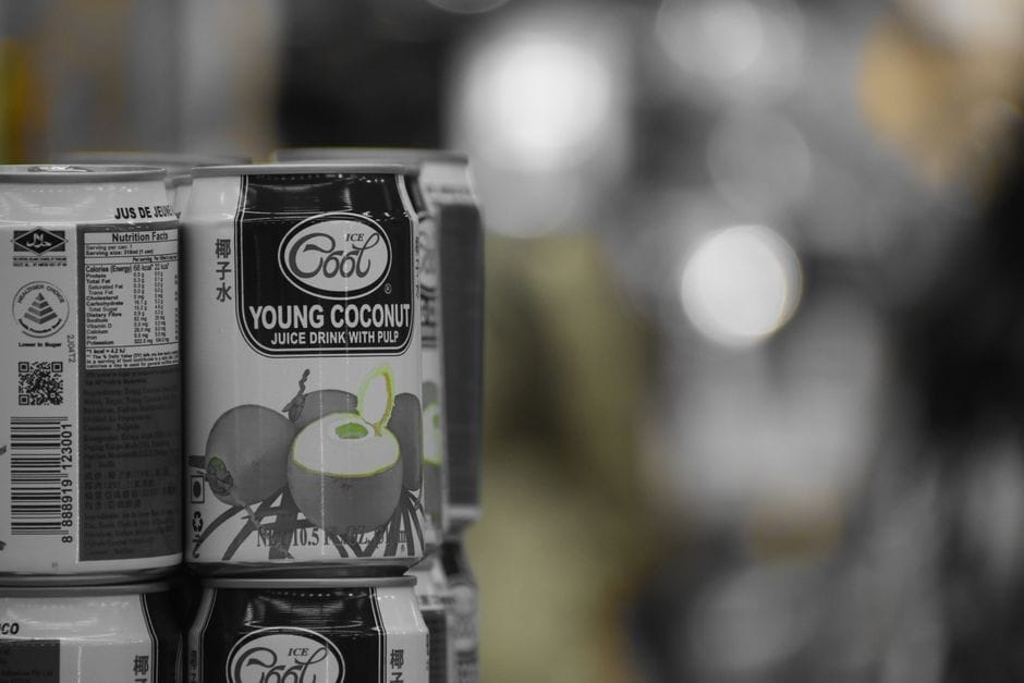 A stack of young coconut juice cans on a shelf with a retail background.