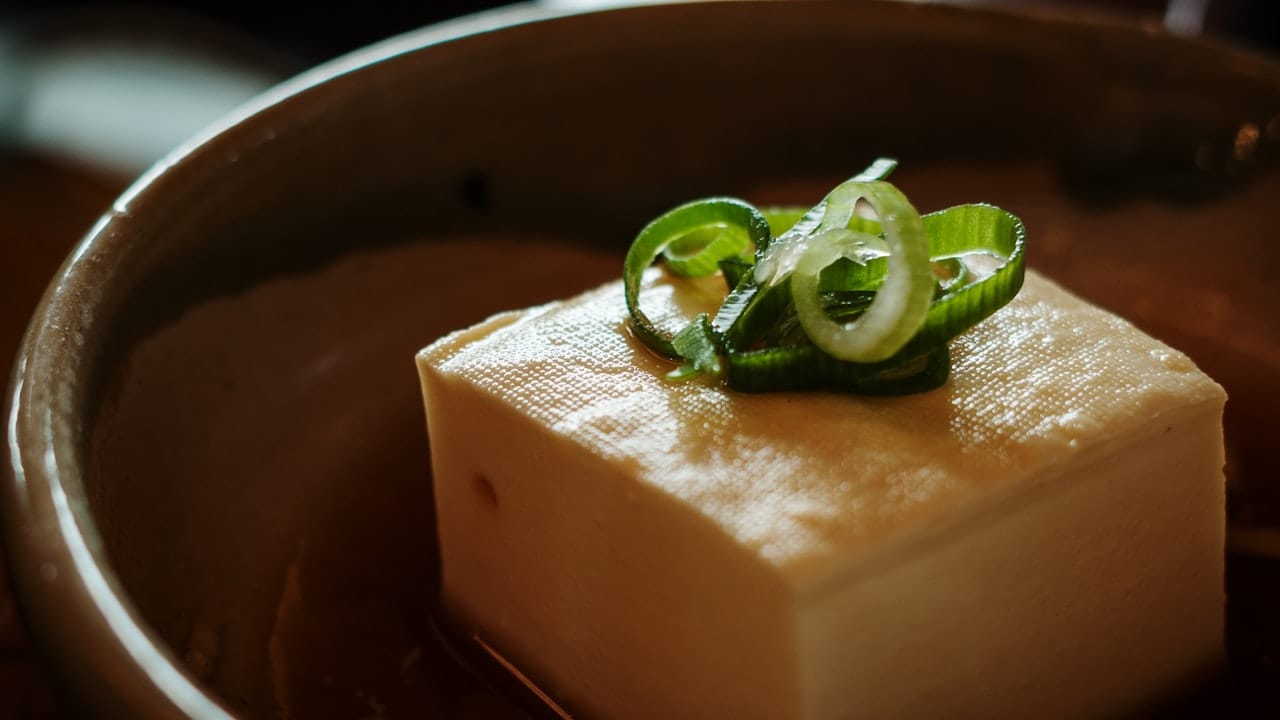 A block of tofu topped with sliced green onions.