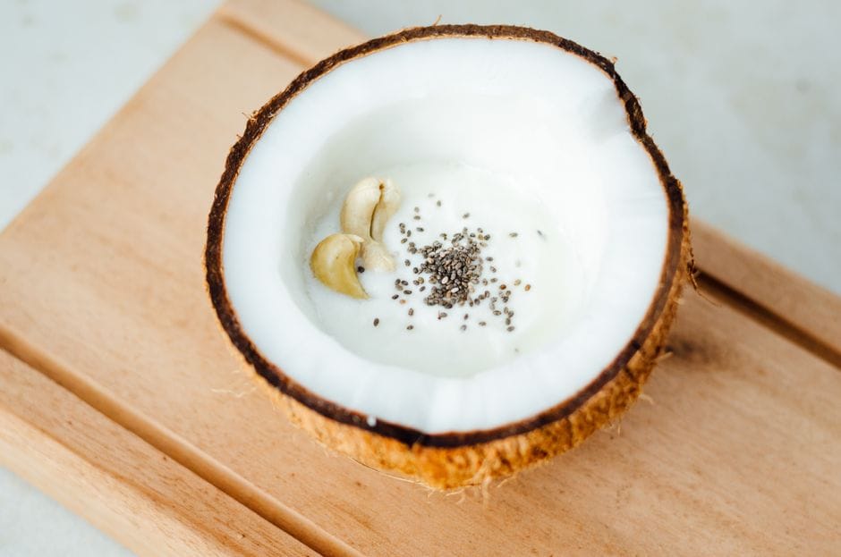 Delicious coconut filled with yogurt, chia seeds, and cashews on a wooden board. Perfect healthy snack.