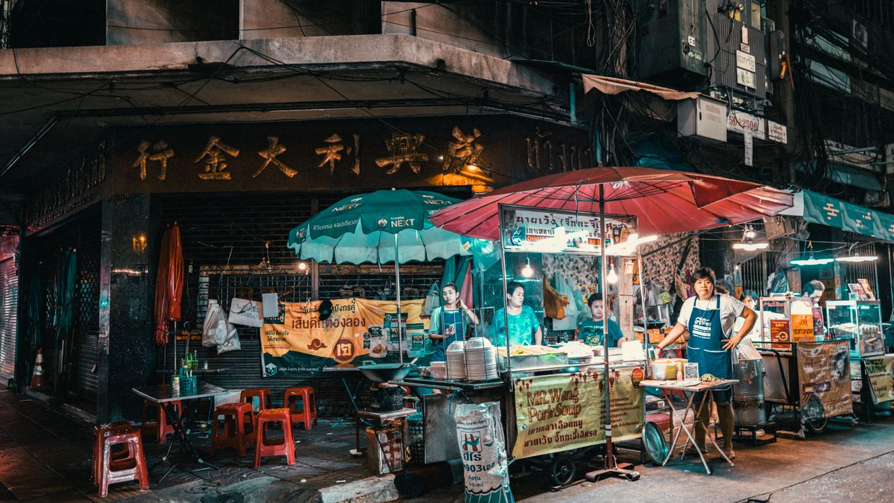 Vibrant night market scene in Bangkok showcasing street food vendors and bustling activity.